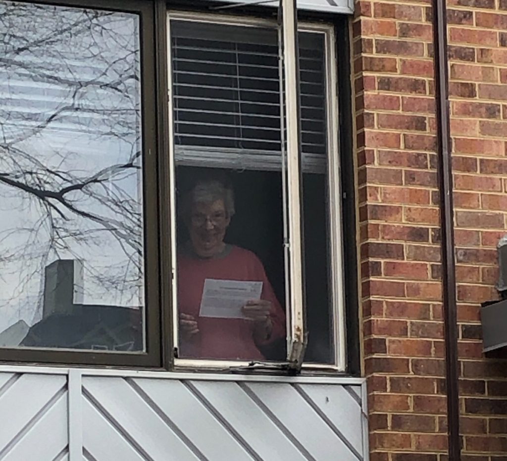 senior resident looks out window during social distancing event