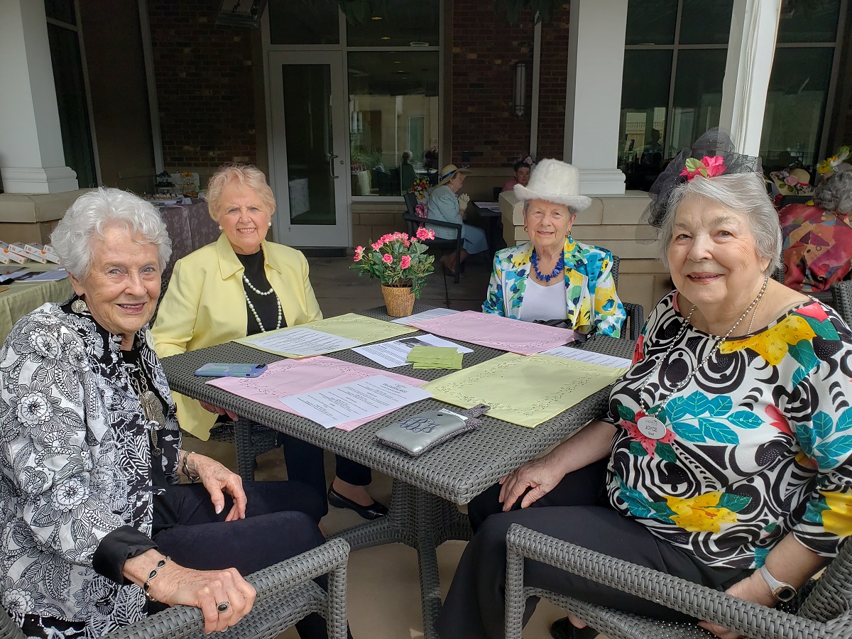 A group of senior women sit outside and enjoy a meal alfresco