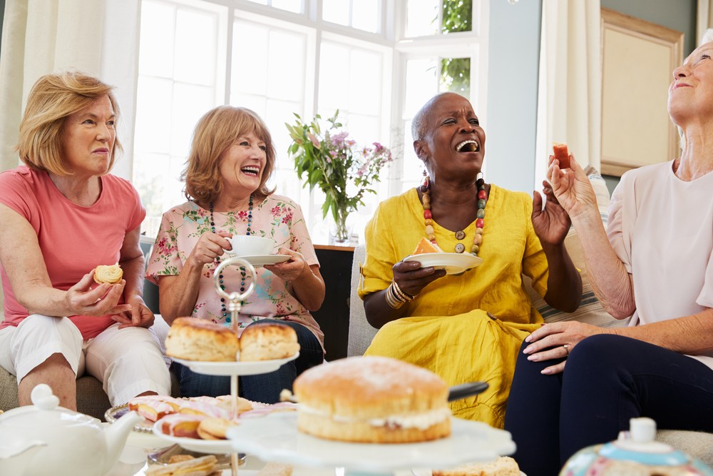 Senior friends laughing and having pastries and tea