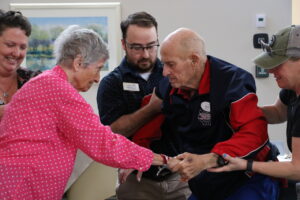 A senior man stands up with assistance.