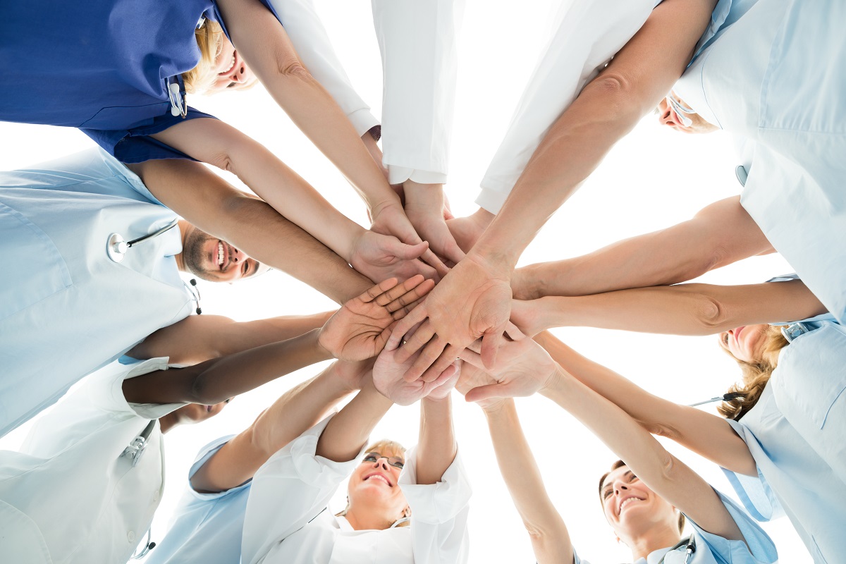 team of skilled nursing stacking hands for encouragement