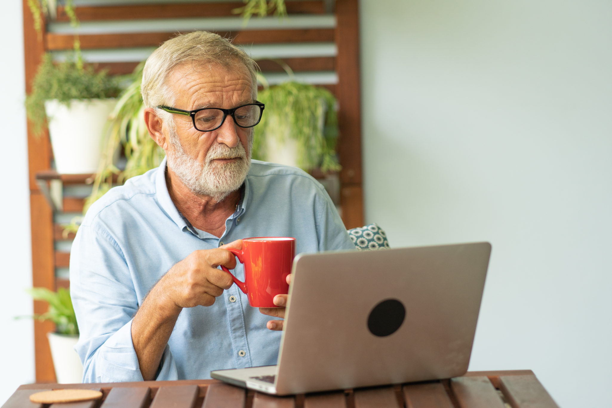 senior man drinking coffee and on laptop