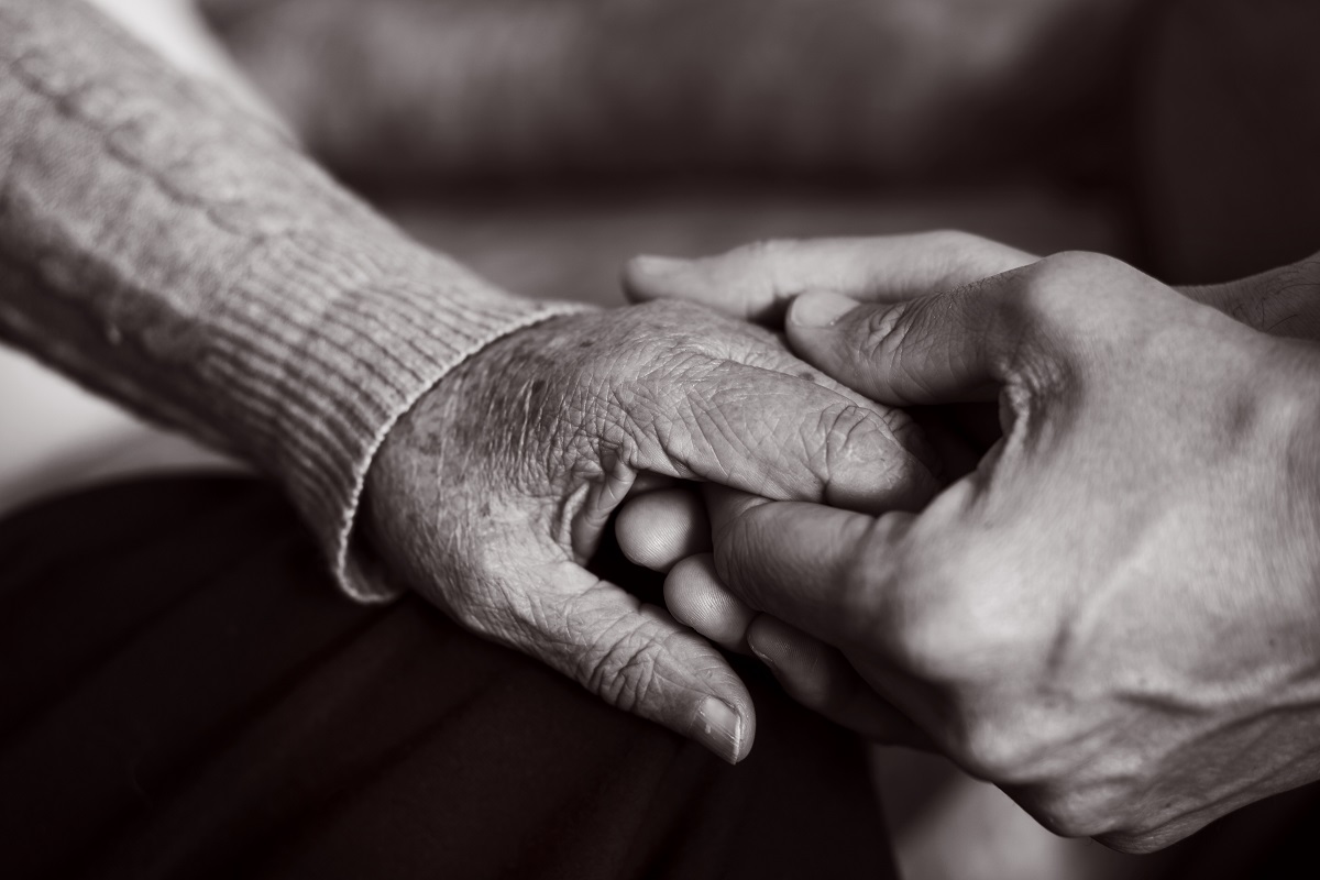 young man holding the hand of an old woman