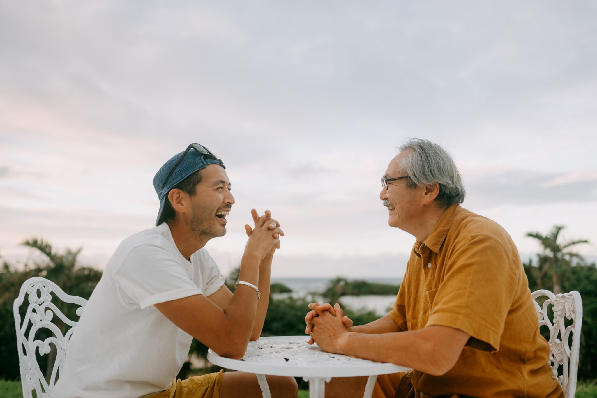 Senior father and adult son chatting on patio