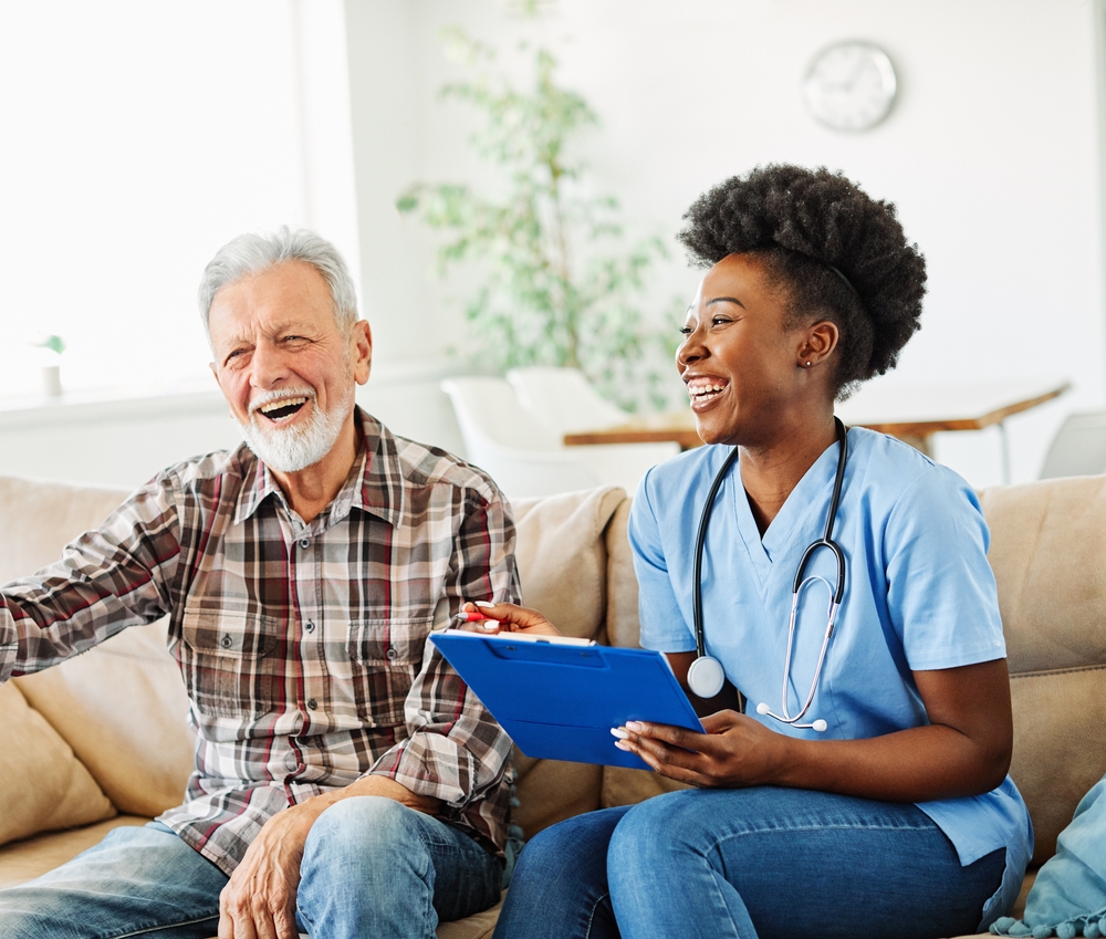 A health care professional laughs and talks with a senior man