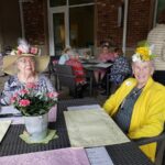 Two senior women wear sunhats decorated with flowers
